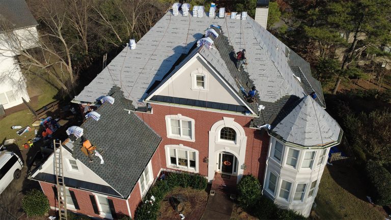 Encompass crew installing underlayment on a brick home with a turret