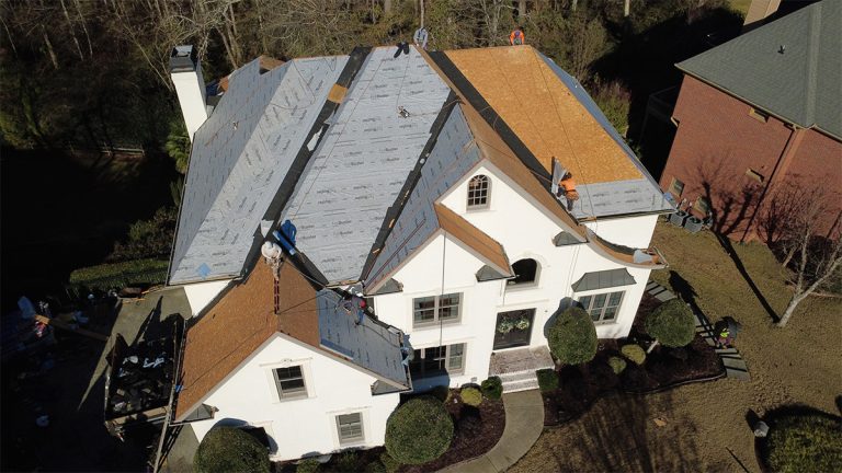 Roof replacement in progress on a white stucco home, new decking and underlayment