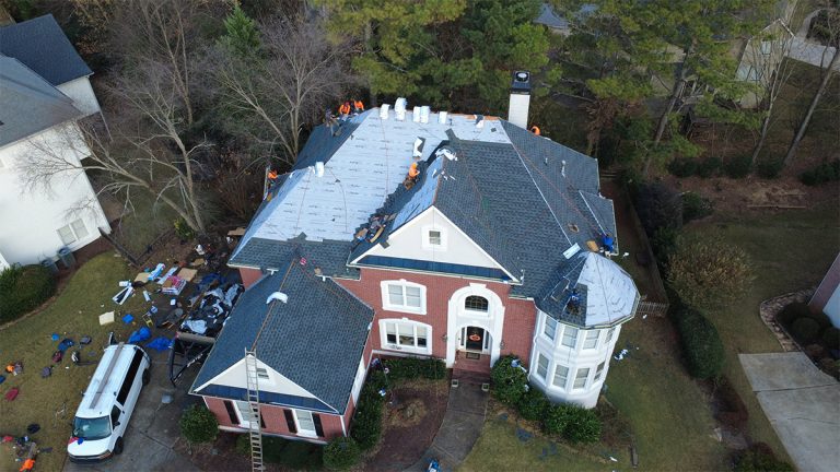 Aerial view of a roof replacement in progress on a brick home with a turret