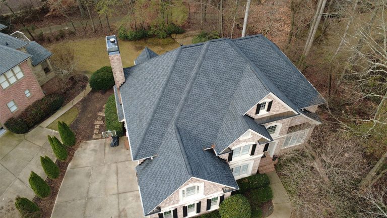 Finished dark gray shingle roof on a brick and stone home